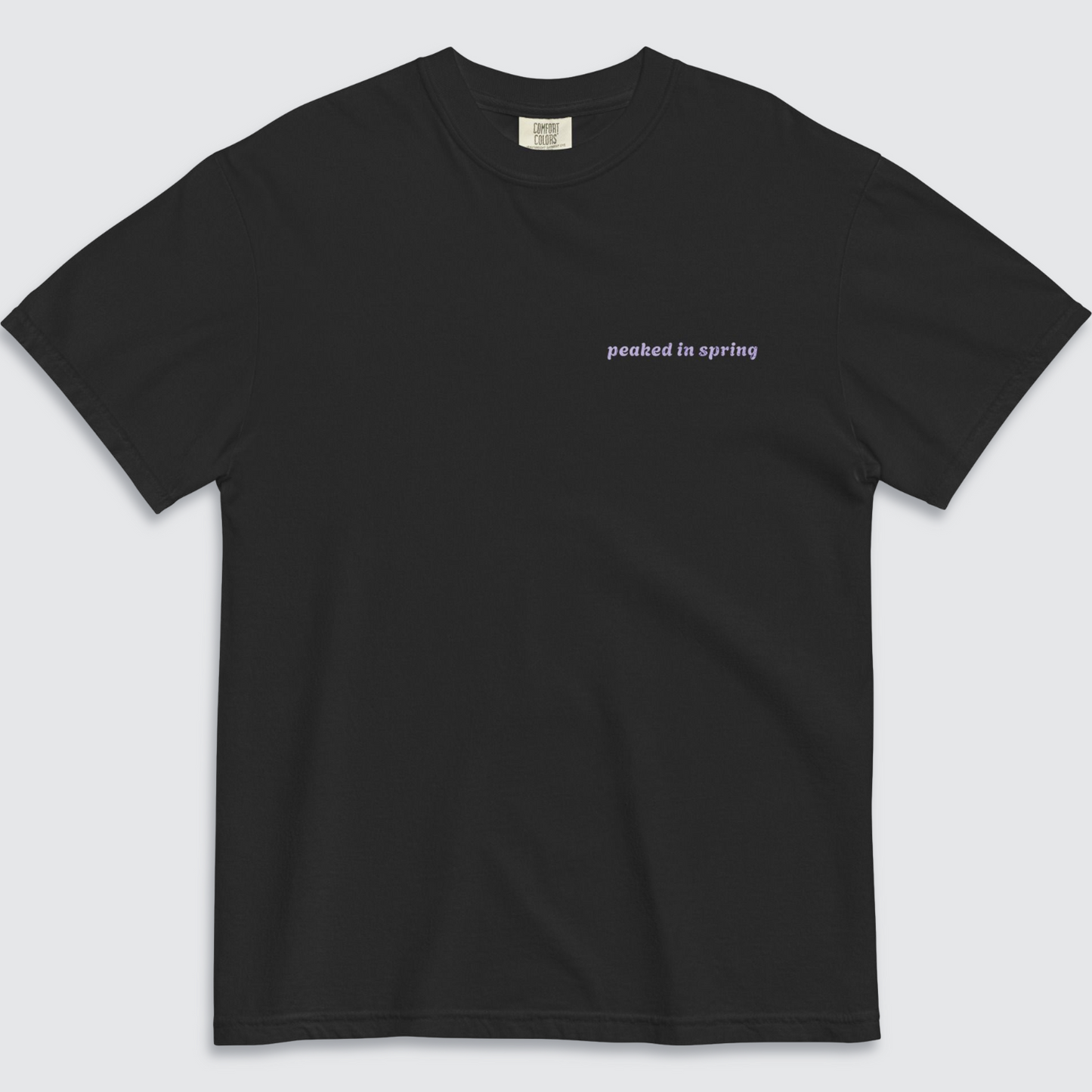 Front of black tshirt with 'peaked in spring' written on the left chest in lilac