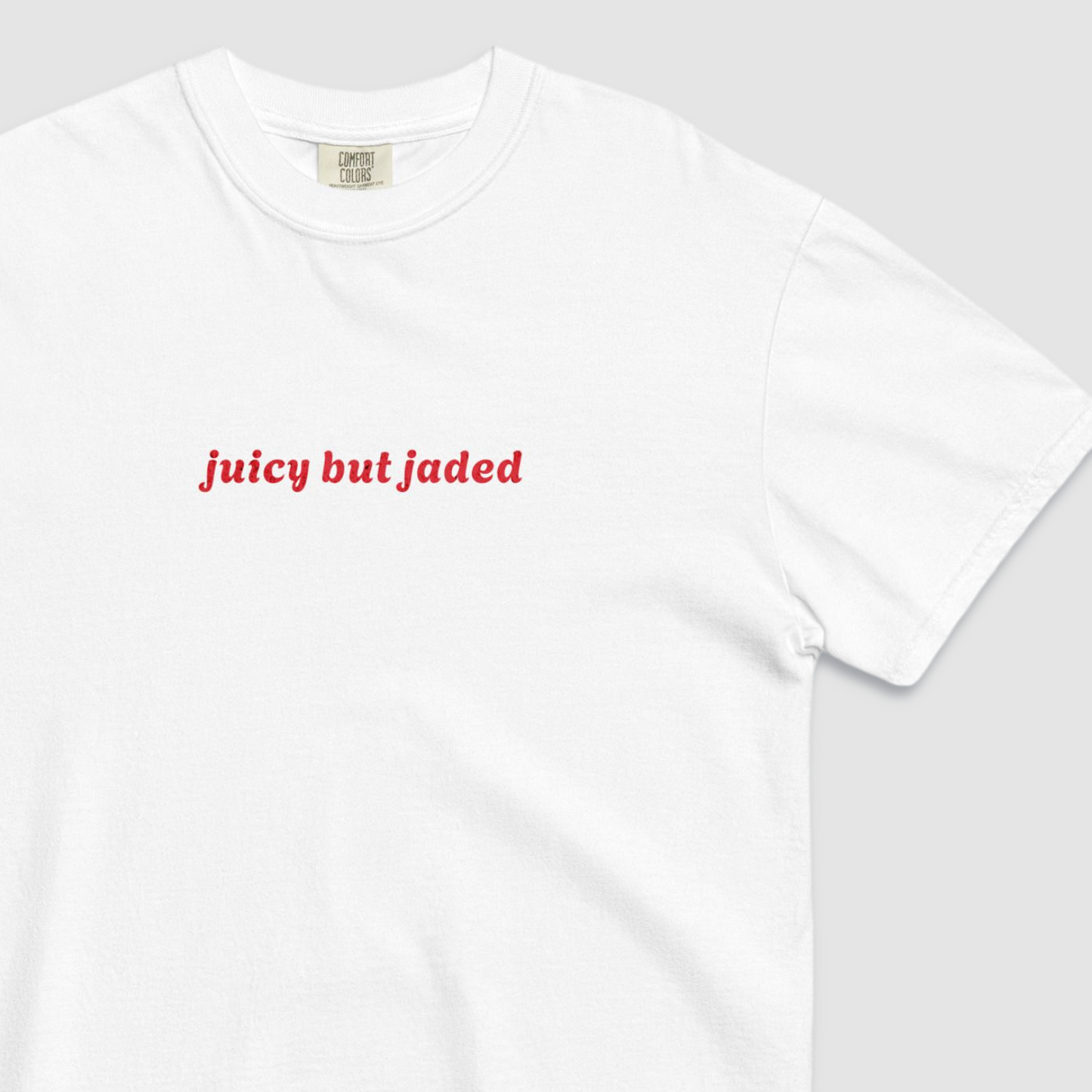 Close up of white tshirt with text 'juicy but jaded' written across the chest in red