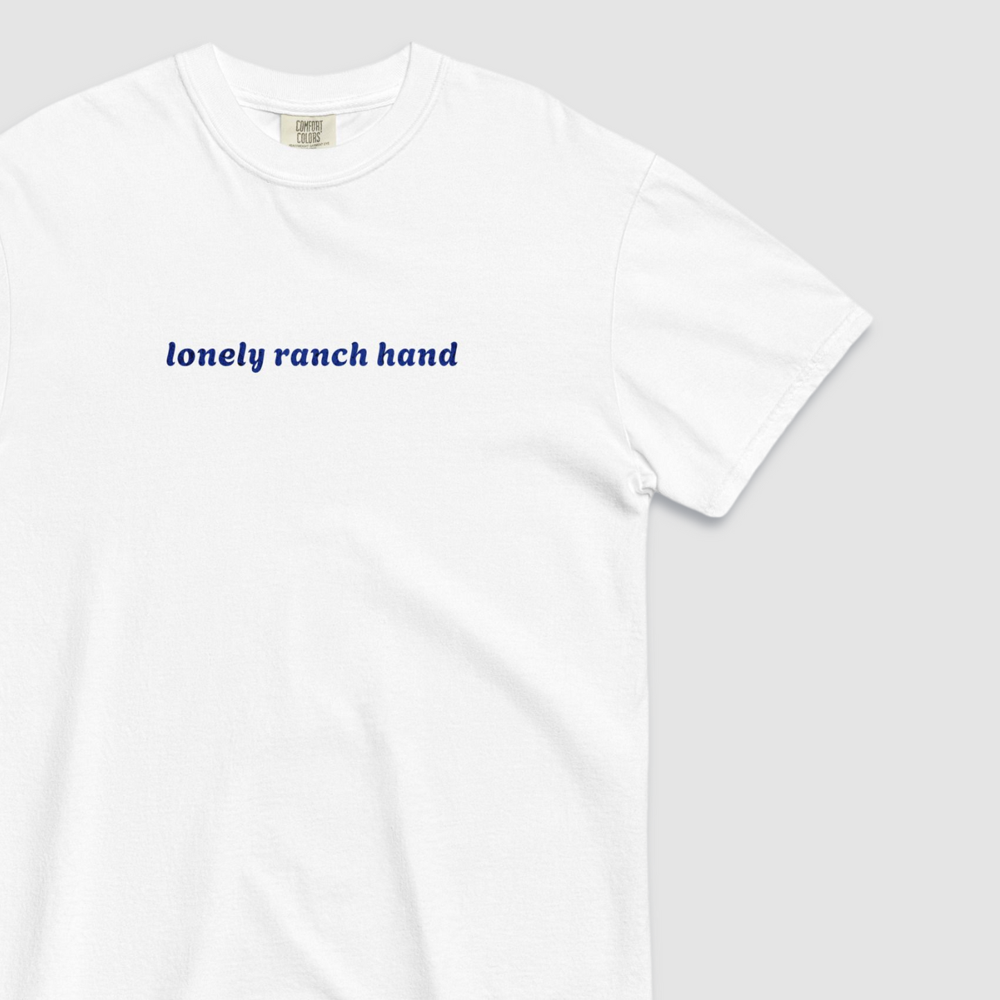 Close up white tshirt with 'lonely ranch hand' text written in blue across the chest