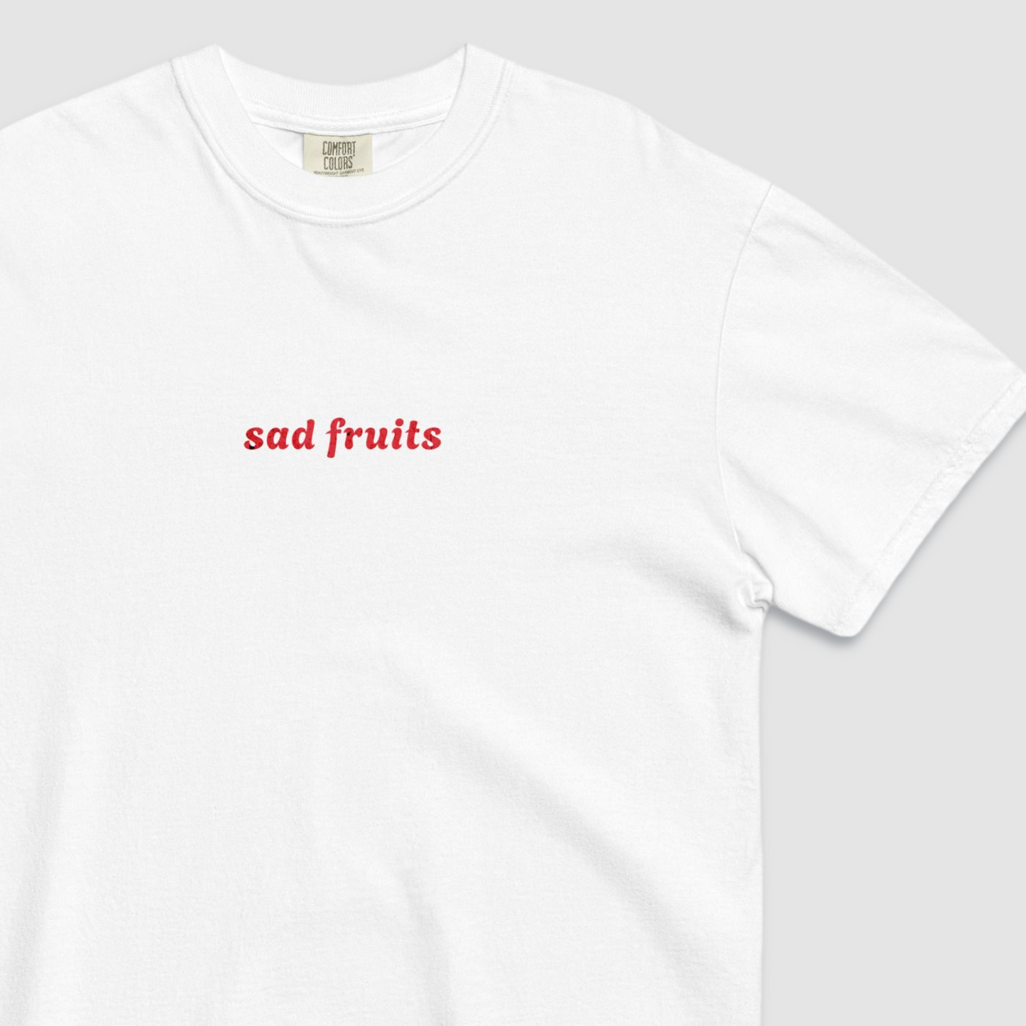 Close up of white tshirt with 'sad fruits' written in red text across the chest
