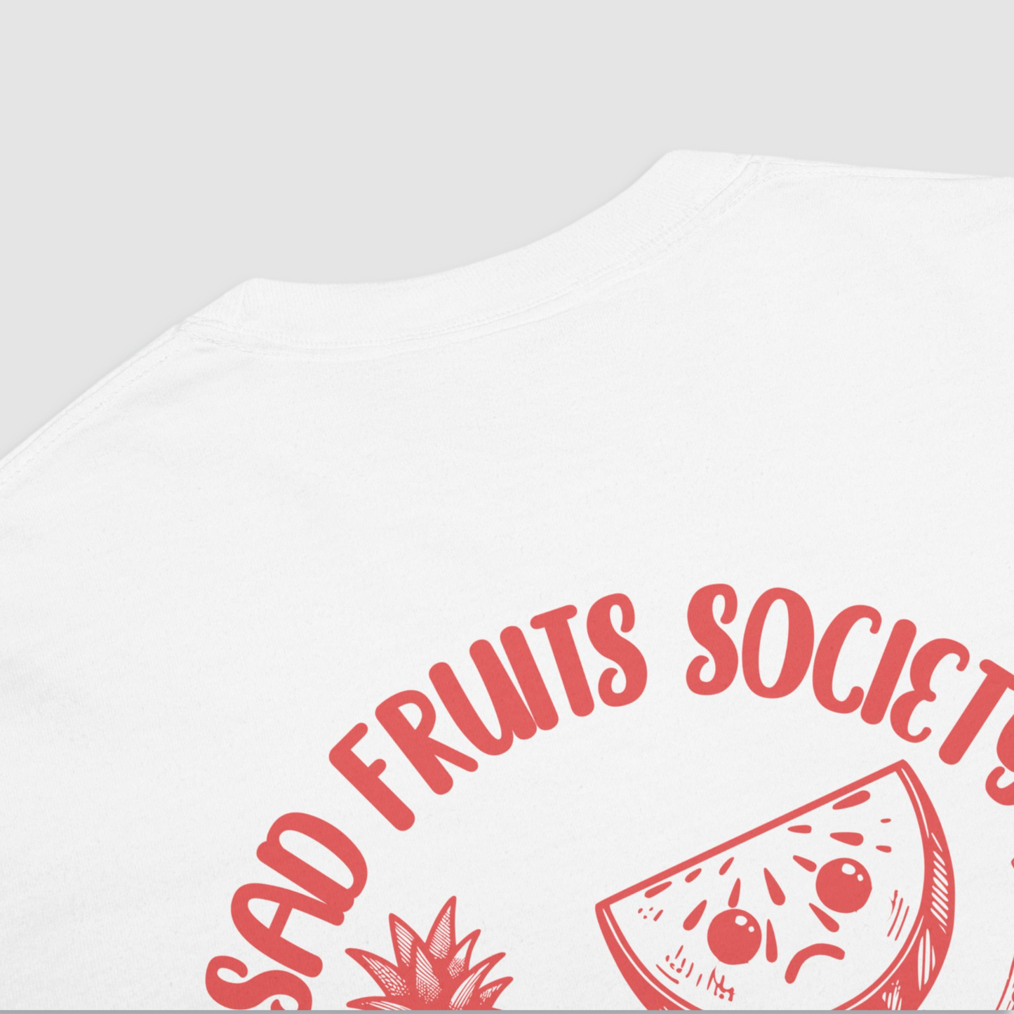 Close up of back of white tshirt with a graphic of a watermelon with a sad face on it with text above saying 'sad fruits society' in red