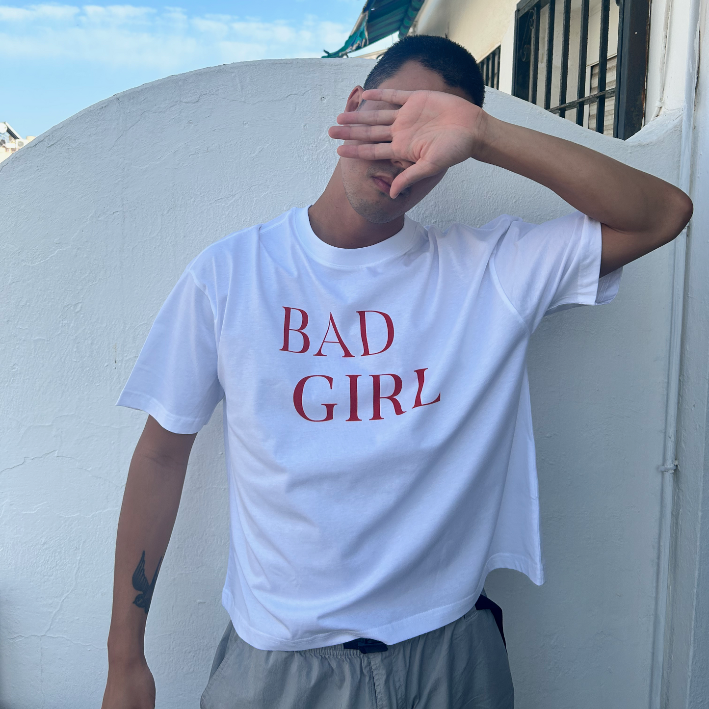 white bad girl tshirt on male model with hand over his face