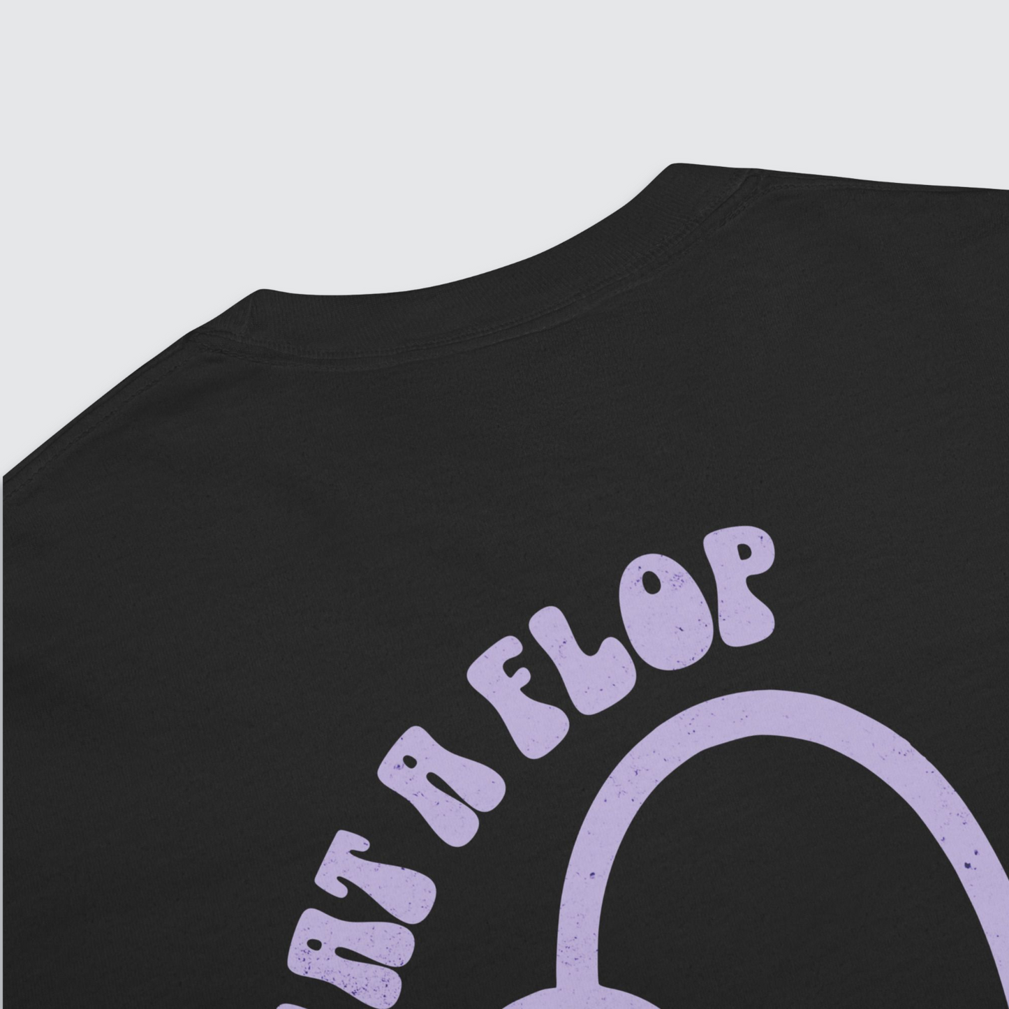 Close up back of black graphic tshirt with a tulip flopped over and 'what a flop' written above the tulip in a lilac colour palatte