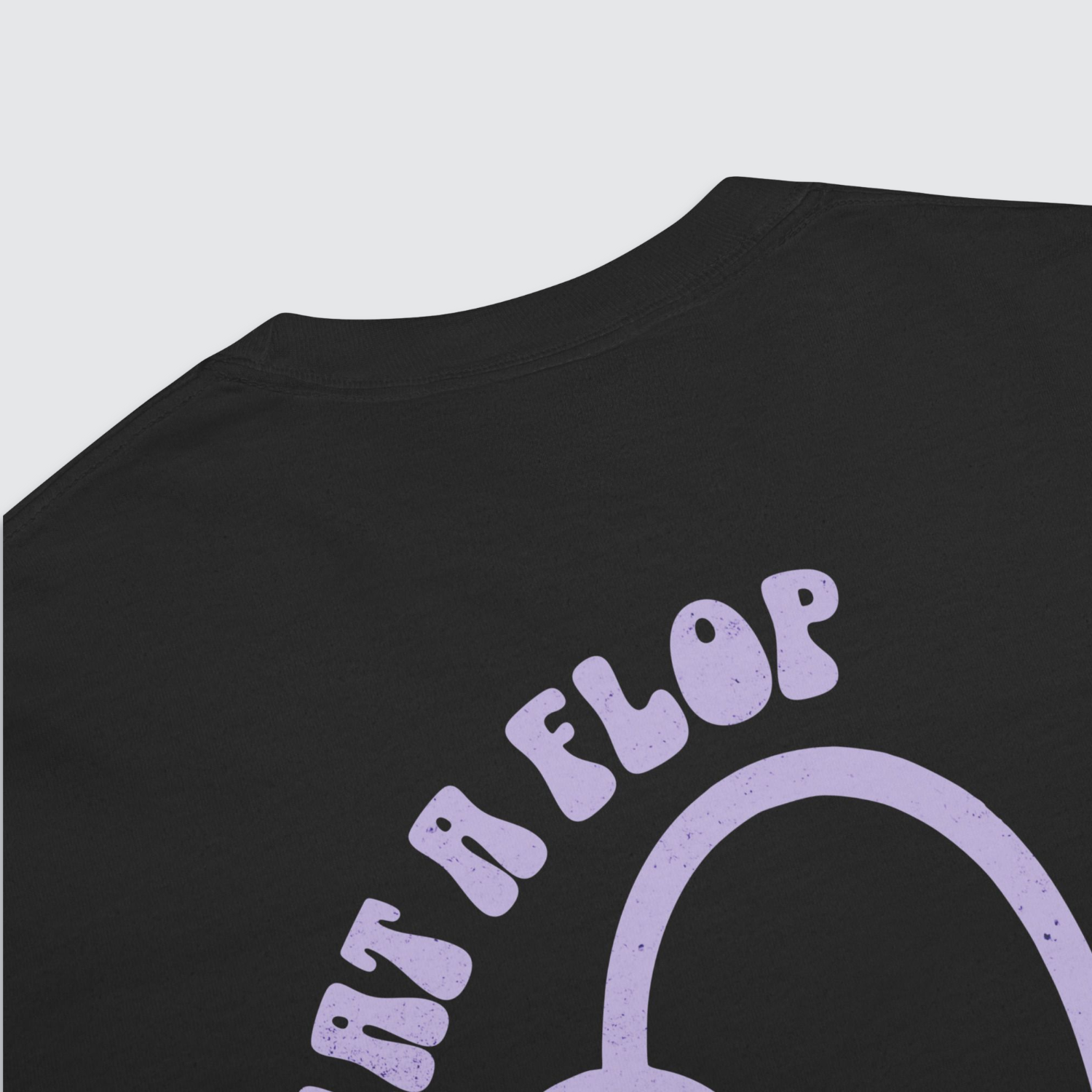 Close up back of black graphic tshirt with a tulip flopped over and 'what a flop' written above the tulip in a lilac colour palatte
