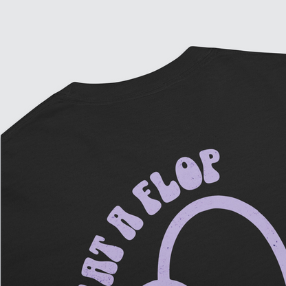 Close up back of black graphic tshirt with a tulip flopped over and 'what a flop' written above the tulip in a lilac colour palatte