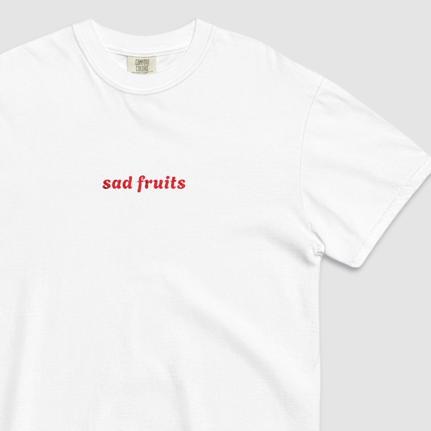 Close up of white tshirt with 'sad fruits' written in red text across the chest